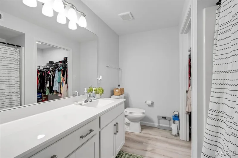 The primary bathroom offers a generous vanity, clean white finishes, bright modern lighting, and a seamless connection to the walk-in closet. — 4101 Spring Creek Lane, O'Fallon, MO 63368