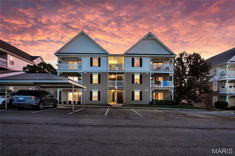 Beautiful twilight photo highlighting the property's exterior, covered parking, and warm interior lighting under a vivid evening sky. — 4101 Spring Creek Lane, O'Fallon, MO 63368