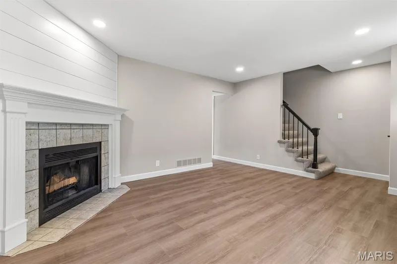 Cozy wood burning fireplace featuring ceramic tile surround, wood mantle & stylish ship lap wall — 39 Park Charles Boulevard S #D, St Peters, MO 63376