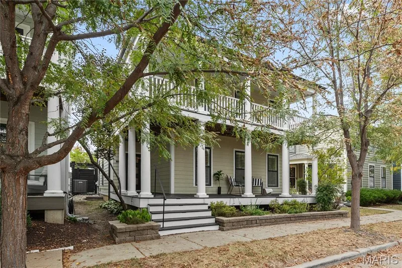 Two-story residence featuring a porch, an upper-level balcony, exterior siding, and mature trees — 3222 Starkville Street, St Charles, MO 63301