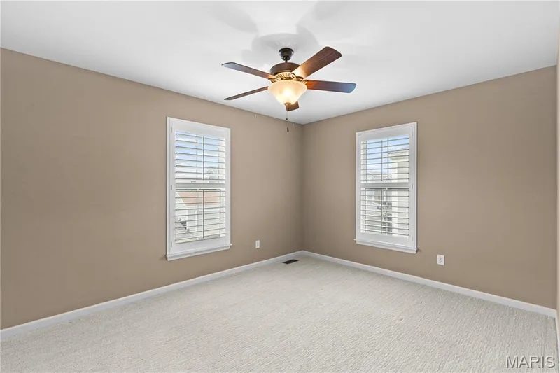 Two windows with louvered shutters, ceiling fan with integrated lighting, and neutral-toned wall paint — 3222 Starkville Street, St Charles, MO 63301