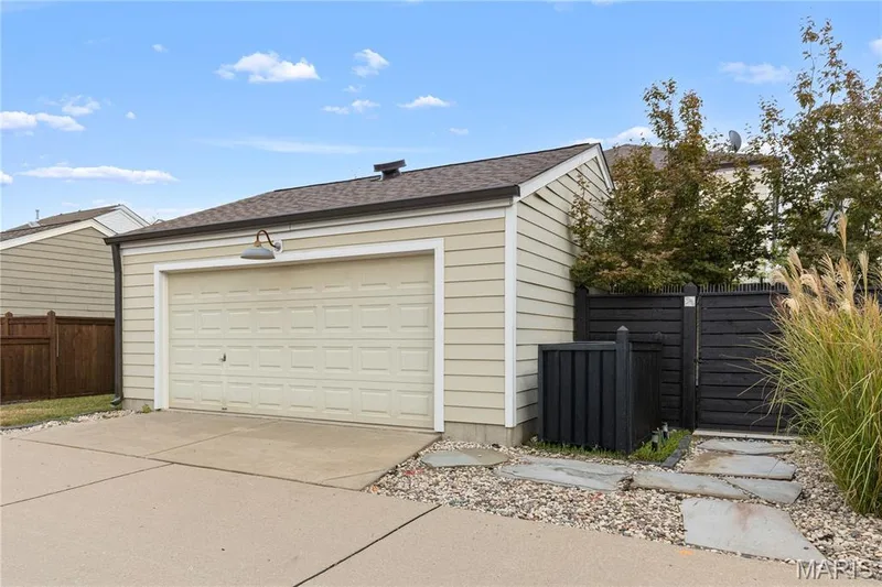 Detached garage with a panel-style door, exterior light fixture, and horizontal siding — 3222 Starkville Street, St Charles, MO 63301