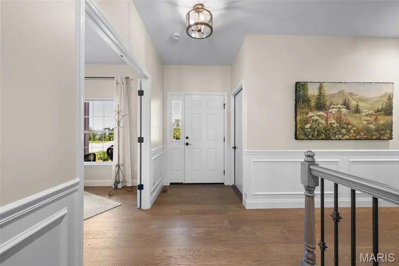 Entryway featuring a single-panel front door with sidelights, wood-finish flooring, wainscoting, and a semi-flush mount light fixture — 193 Santa Elena Drive, Wentzville, MO 63385