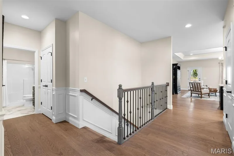 Hardwood flooring throughout, white wainscoting, recessed lighting, and a wrought iron and wood banister — 193 Santa Elena Drive, Wentzville, MO 63385