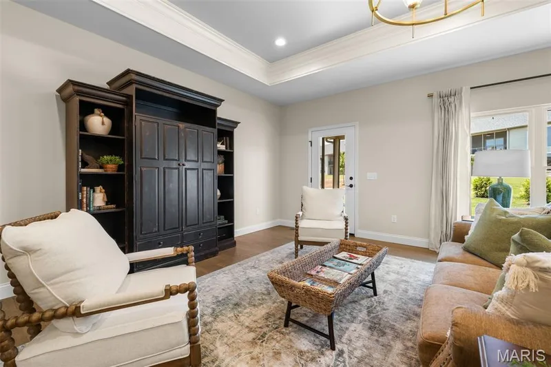 Tray ceiling with crown molding, recessed lighting, wood-finish flooring, and built-in dark wood cabinetry — 193 Santa Elena Drive, Wentzville, MO 63385