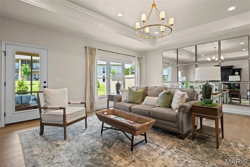 Tray ceiling with an elegant chandelier, recessed lighting, wood-finish flooring, and a glass-paned door — 193 Santa Elena Drive, Wentzville, MO 63385