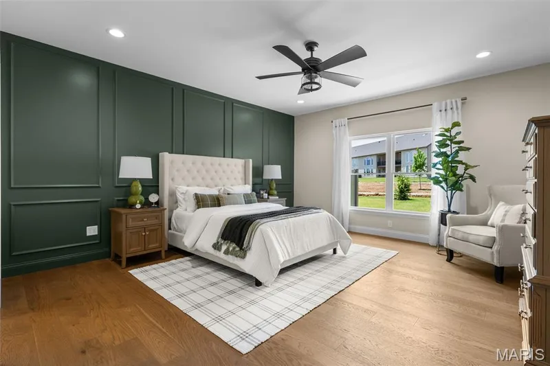 Wood-finish flooring, accent wall with decorative molding, recessed lighting, ceiling fan with integrated light, and large window with white trim — 193 Santa Elena Drive, Wentzville, MO 63385