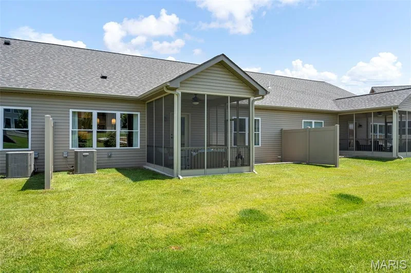 Expansive green lawn with two screened-in porches featuring exterior lighting, a gabled roofline, and neutral-toned siding — 193 Santa Elena Drive, Wentzville, MO 63385