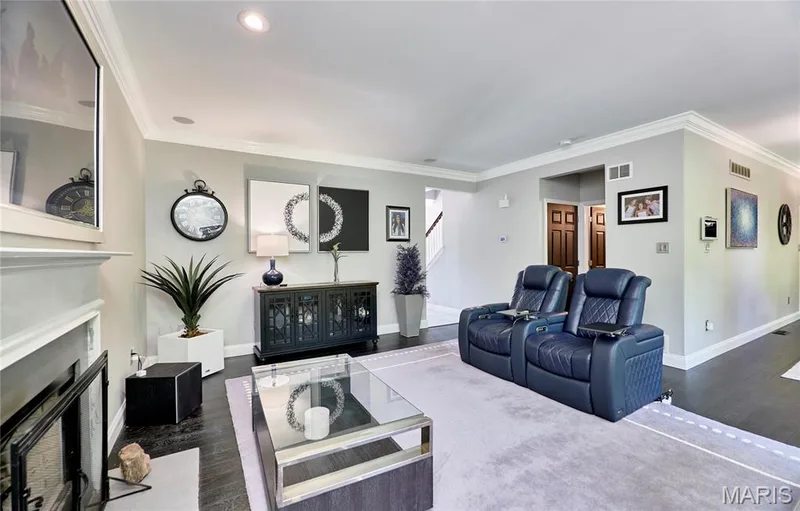 Sophisticated living room showcasing recessed ceiling lighting, a black built-in media console with glass-front cabinetry, and dark wood-finish flooring throughout — 264 Greenshire Lane, Dardenne Prairie, MO 63368