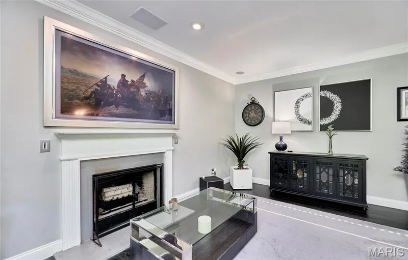 Elegant living room featuring a gas fireplace with white surround and mantel, polished stone flooring, recessed ceiling lighting, and a black media console with glass-front cabinetry — 264 Greenshire Lane, Dardenne Prairie, MO 63368