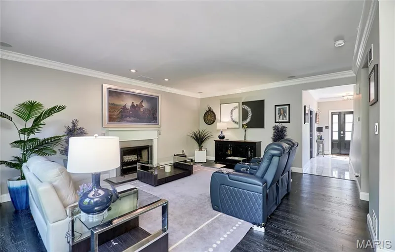 Elegant living room showcasing a coffered ceiling with recessed lighting, fireplace with dark surround, and dark wood-finish flooring throughout — 264 Greenshire Lane, Dardenne Prairie, MO 63368