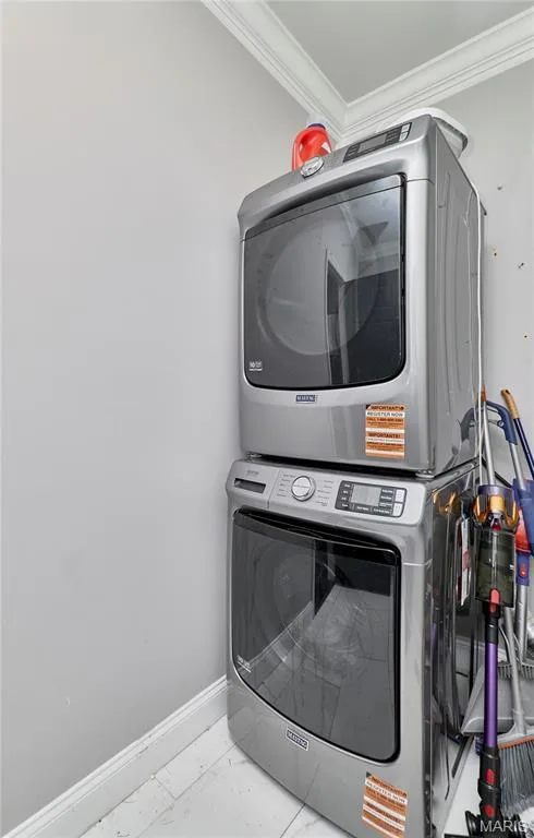 Dedicated laundry room featuring stacked washer and dryer units with modern controls, white cabinetry, and organized storage solutions along the side wall — 264 Greenshire Lane, Dardenne Prairie, MO 63368
