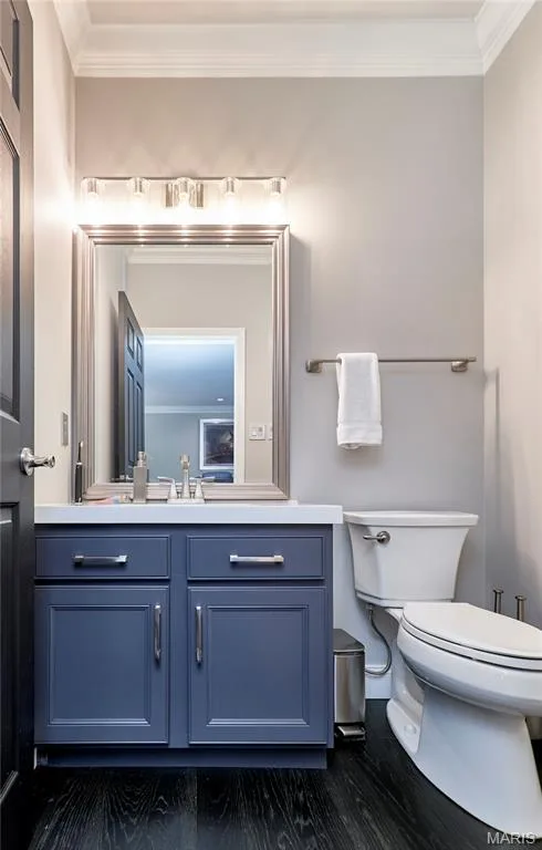 Spa-inspired bathroom featuring a navy blue vanity with dual drawers and brushed nickel hardware, white quartz countertop, framed mirror with integrated lighting, and dark wood-finish flooring — 264 Greenshire Lane, Dardenne Prairie, MO 63368