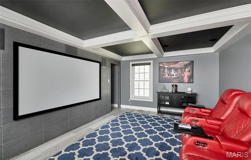 Media room featuring a large projection screen, coffered ceiling, and wood-finish flooring — 264 Greenshire Lane, Dardenne Prairie, MO 63368