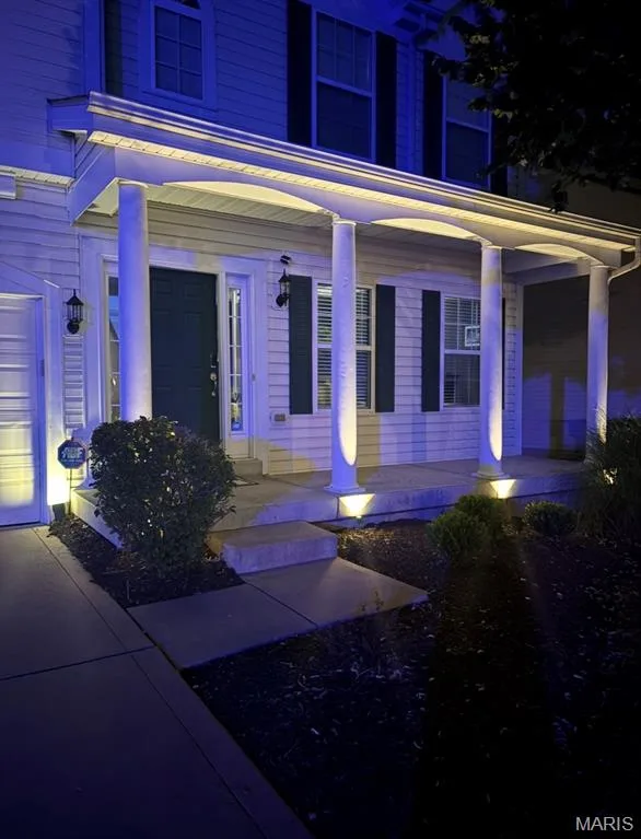 Welcoming front entry showcasing a covered portico with classical columns, recessed soffit lighting, and dual panel doors with sidelights — 264 Greenshire Lane, Dardenne Prairie, MO 63368