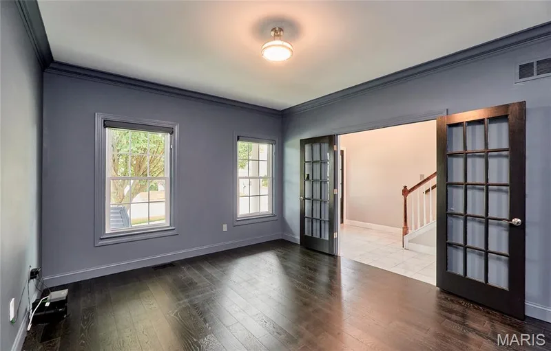 Dark wood-finish flooring, dual windows, crown molding, and double French doors with dark frames — 264 Greenshire Lane, Dardenne Prairie, MO 63368