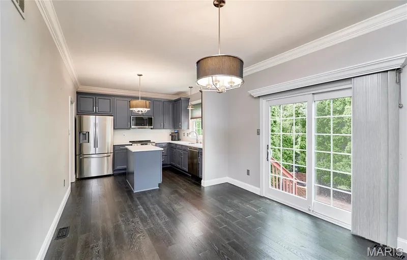 Dark wood-finish flooring, white crown molding, pendant lighting, sliding glass door, and shaker-style cabinetry — 264 Greenshire Lane, Dardenne Prairie, MO 63368