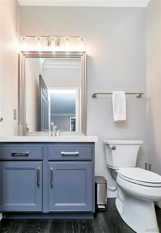 Powder room featuring a blue vanity with brushed nickel hardware, a white countertop, a framed mirror, and wood-finish flooring — 264 Greenshire Lane, Dardenne Prairie, MO 63368
