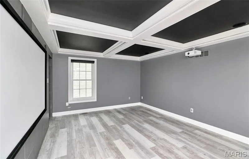 Coffer-style ceiling with dark inserts, large projection screen, light wood-finish flooring, and a mounted projector — 264 Greenshire Lane, Dardenne Prairie, MO 63368