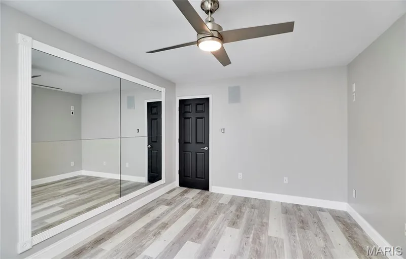 Mirrored wall paneling, ceiling fan with integrated lighting, two paneled doors, and wood-finish flooring — 264 Greenshire Lane, Dardenne Prairie, MO 63368