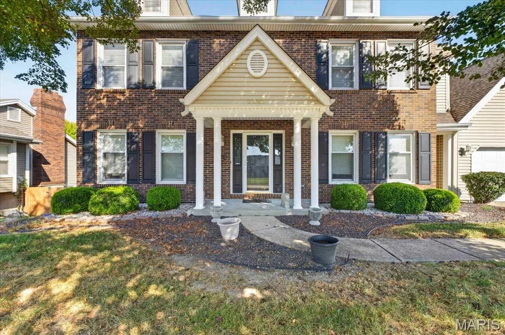 Brick facade, prominent front gable, white columned porch, dormer windows, and dark louvered shutters — 3445 Riverchase Parkway, St Charles, MO 63301