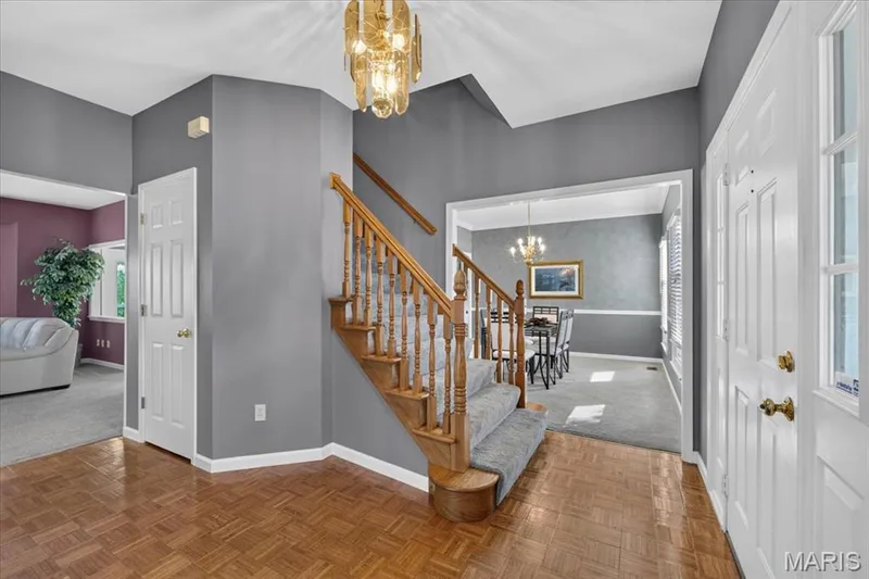 Parquet flooring, wood staircase with carpeted treads, chandelier, white paneled doors, and a decorative archway — 3445 Riverchase Parkway, St Charles, MO 63301