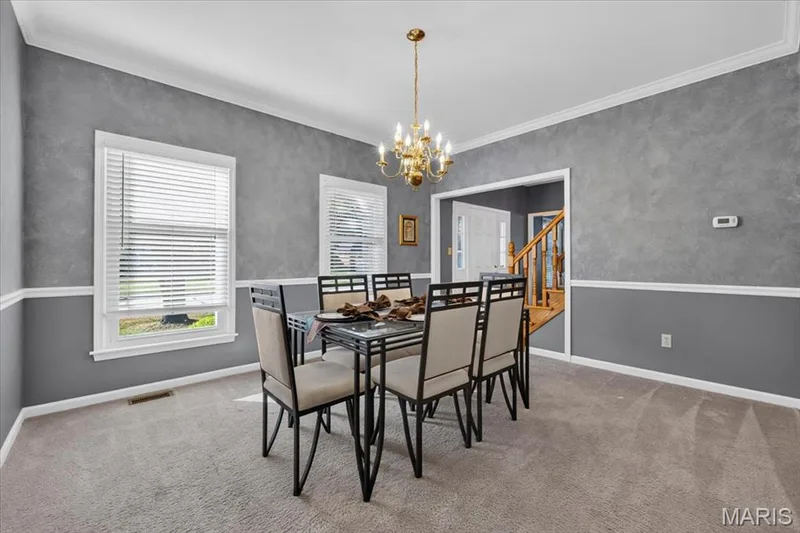 Formal dining area featuring textured grey walls, white chair rail molding, and crown molding — 3445 Riverchase Parkway, St Charles, MO 63301