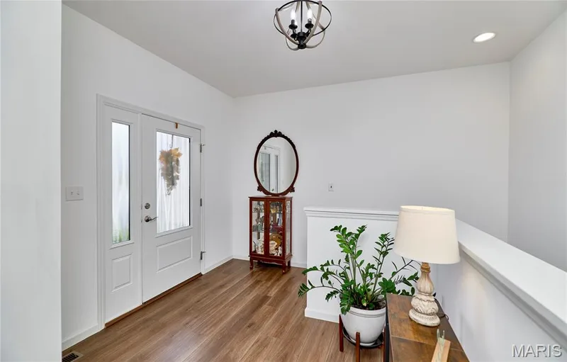 Entry with wood-finish flooring, a white paneled door with glass inserts, and a decorative ceiling light fixture — 305 Copperfield Court, St Charles, MO 63301