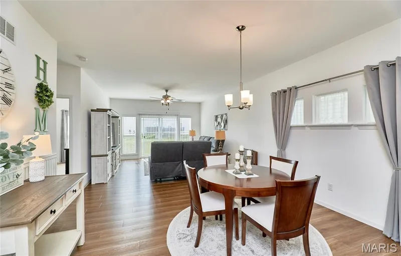 Open-concept living area featuring wood-finish flooring, a contemporary chandelier, and sliding glass doors — 305 Copperfield Court, St Charles, MO 63301