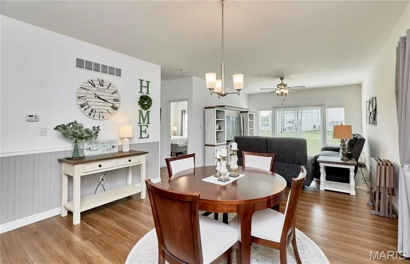Wood-finish flooring throughout, board and batten wall detailing, pendant light fixture, ceiling fan, and sliding glass door to exterior — 305 Copperfield Court, St Charles, MO 63301