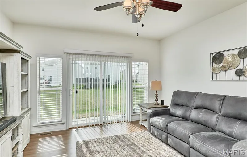 Hardwood-finish flooring, sliding glass door, white walls, and a ceiling fan with integrated lighting — 305 Copperfield Court, St Charles, MO 63301