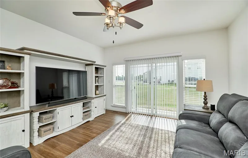 Vaulted ceiling with a ceiling fan, wood-finish flooring, sliding glass door, and vertical blinds — 305 Copperfield Court, St Charles, MO 63301