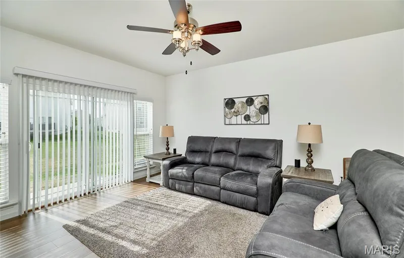 Sliding glass door with vertical blinds, wood-finish flooring, and a ceiling fan with integrated lighting — 305 Copperfield Court, St Charles, MO 63301
