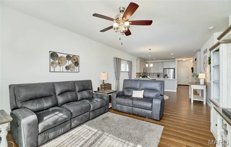 Open-concept living area with wood-finish flooring, a ceiling fan with integrated lighting — 305 Copperfield Court, St Charles, MO 63301