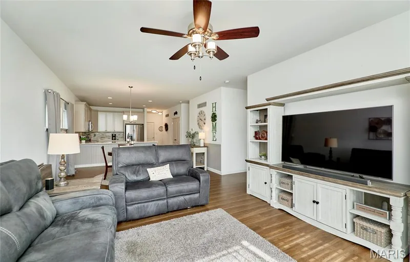Integrated living space featuring wood-finish flooring, a ceiling fan, and white walls — 305 Copperfield Court, St Charles, MO 63301