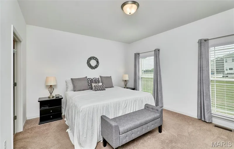 Carpeted flooring, white walls, and two large windows with blinds and curtains — 305 Copperfield Court, St Charles, MO 63301