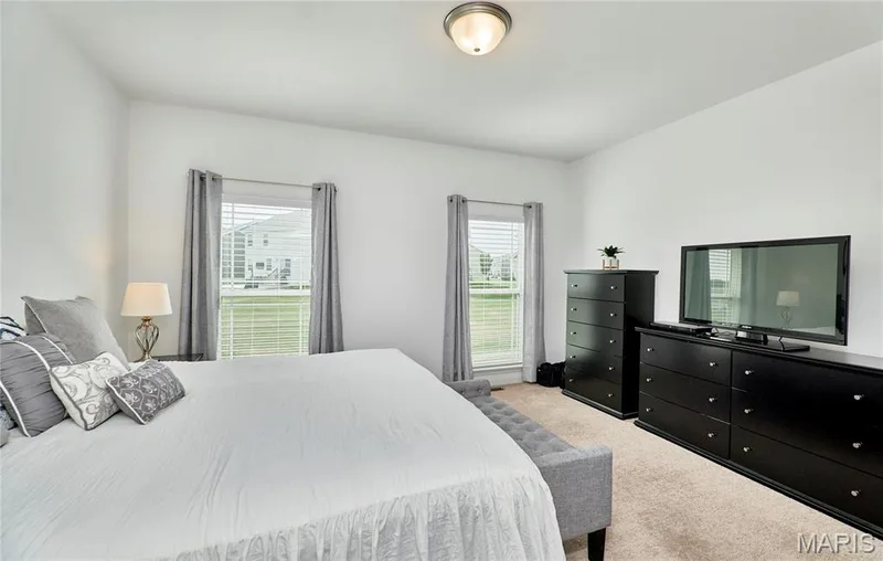 Carpeted room featuring dual windows with blinds, a flush mount ceiling light, and ample wall space — 305 Copperfield Court, St Charles, MO 63301