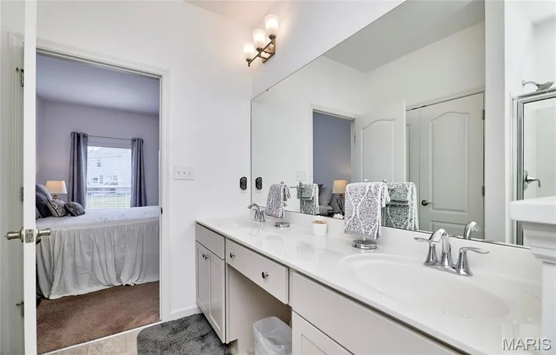 Dual vanity with white countertops, chrome fixtures, and a large wall-mounted mirror — 305 Copperfield Court, St Charles, MO 63301