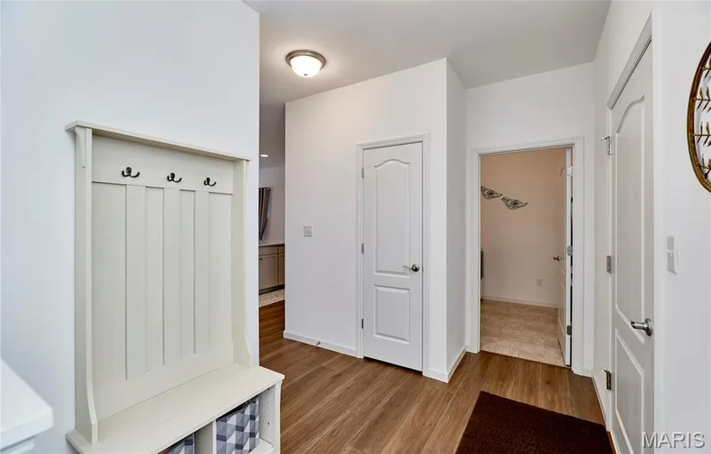 Entryway with wood-finish flooring, built-in hall tree with storage, interior paneled doors, and flush-mount lighting — 305 Copperfield Court, St Charles, MO 63301