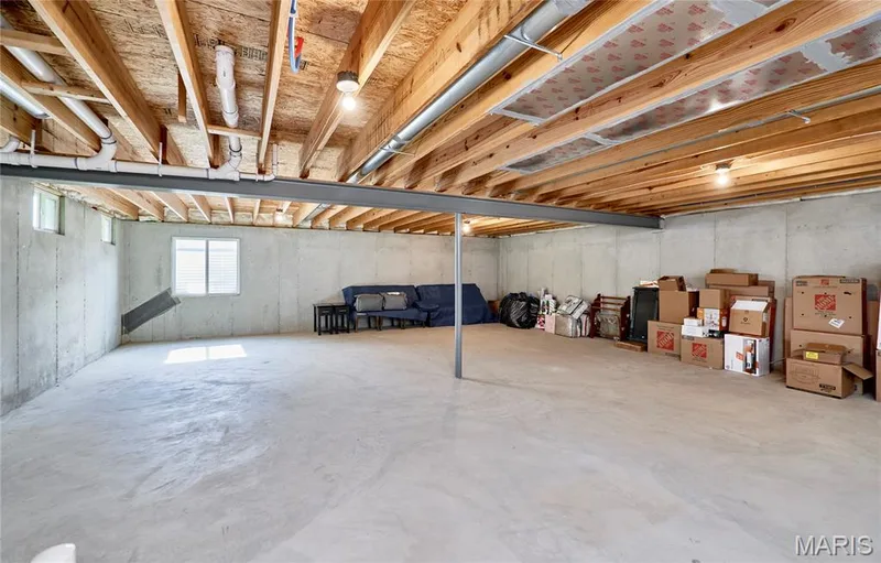 Unfinished basement featuring concrete flooring, exposed wood joists, structural steel beam, and egress window — 305 Copperfield Court, St Charles, MO 63301
