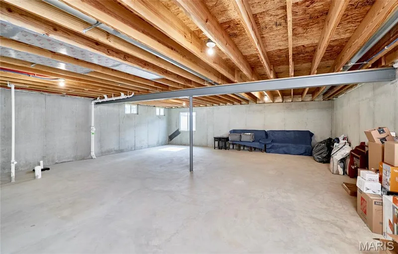 Unfinished basement with concrete flooring, exposed wood ceiling joists, concrete foundation walls, and multiple small windows — 305 Copperfield Court, St Charles, MO 63301