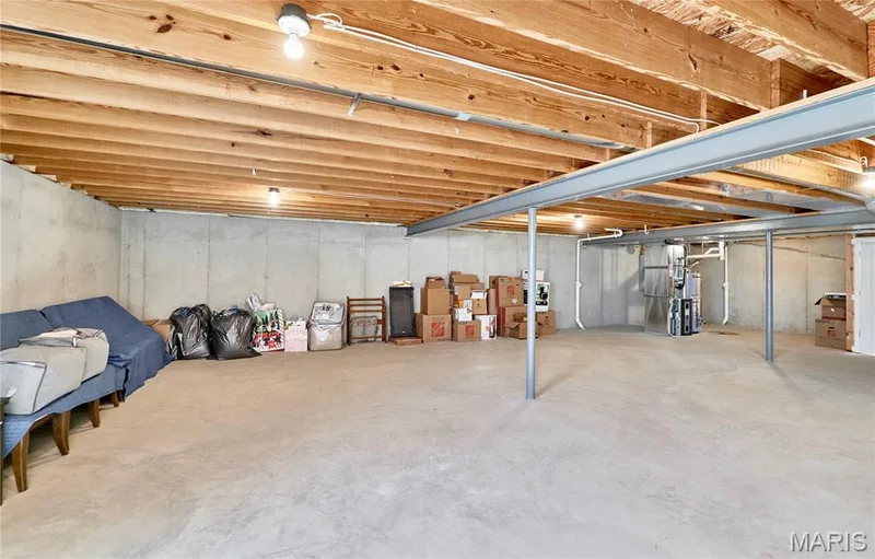 Unfinished basement featuring concrete walls and flooring, exposed wood beam ceiling, and structural steel beams — 305 Copperfield Court, St Charles, MO 63301
