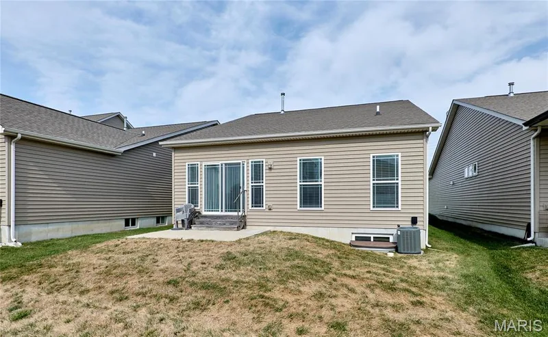 Rear exterior with sliding glass door, concrete patio, and neutral-toned siding — 305 Copperfield Court, St Charles, MO 63301