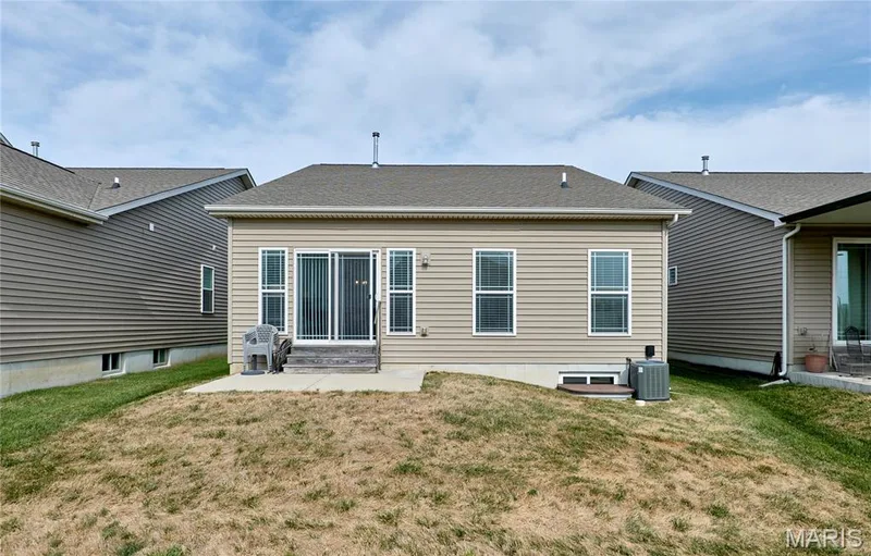 Rear exterior with light tan horizontal siding, a ground-level patio, and sliding glass doors — 305 Copperfield Court, St Charles, MO 63301