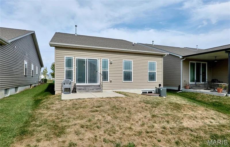 Exterior featuring tan siding, a sliding glass door, multiple windows, and a concrete patio — 305 Copperfield Court, St Charles, MO 63301