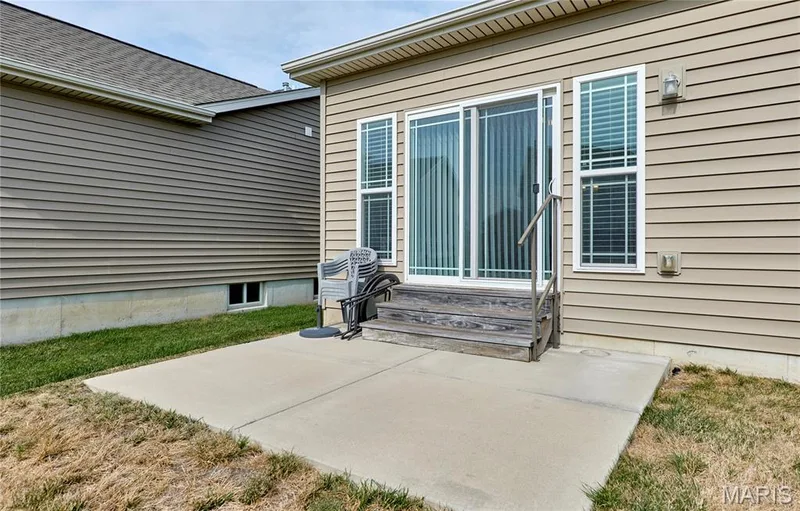 Concrete patio featuring a sliding glass door and exterior wall sconce — 305 Copperfield Court, St Charles, MO 63301