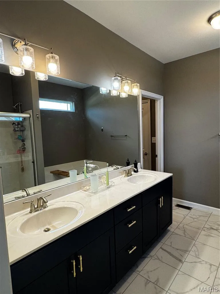 Dual vanity with white countertop, dark cabinetry, and brushed nickel hardware — 401 Copperfield Court, St Charles, MO 63301