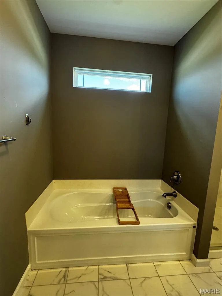 Soaking tub with a shower fixture, tile flooring, and a transom window — 401 Copperfield Court, St Charles, MO 63301