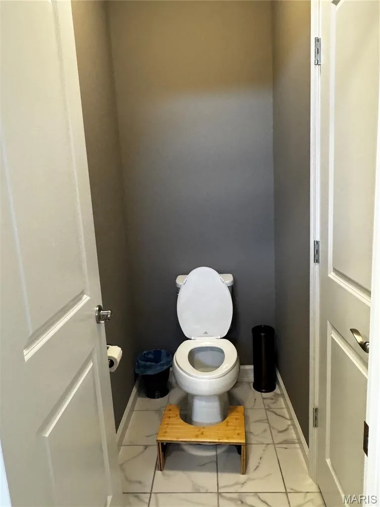 White ceramic toilet with a matching toilet seat and lid, set against dark gray painted walls — 401 Copperfield Court, St Charles, MO 63301