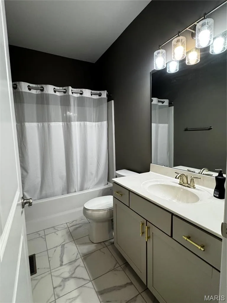 Bathroom featuring a single vanity with built-in sink, gold-finish hardware, a tub/shower combination, and tile flooring — 401 Copperfield Court, St Charles, MO 63301